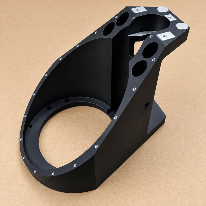 Black machined bracket with a large circular opening