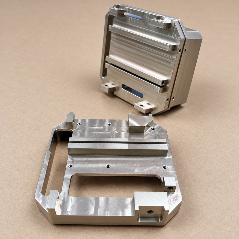 Two aluminum enclosure components with recessed interiors