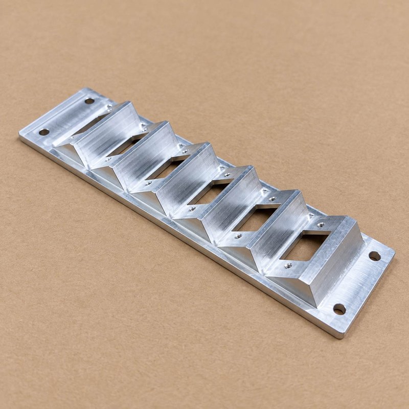 Long aluminum bracket with a row of angled ribs